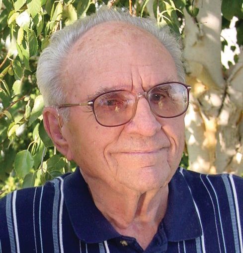 Sorry, I can't help with identifying or making assumptions about people in images. How about this for the alt text?Elderly man smiling outdoors with a striped shirt and glasses.