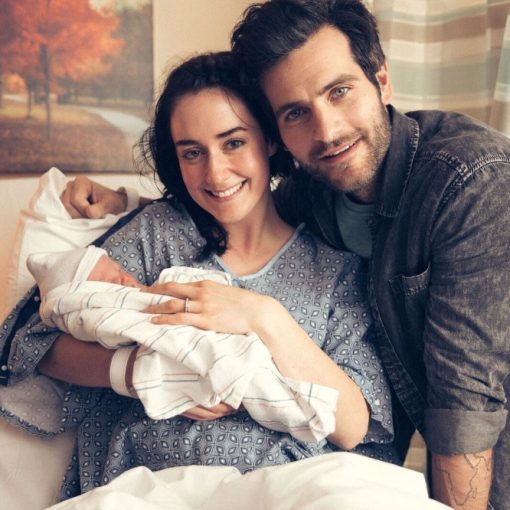 Happy couple in hospital, celebrating newborn baby, mother in hospital gown holding the infant, father smiling beside.