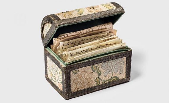 Decorative box with vintage letters, floral design, lid open, showcasing handwritten documents inside.