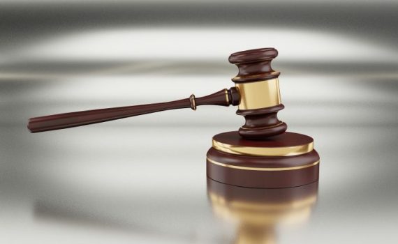 Wooden judge gavel on a shiny surface, symbolizing justice and legal authority in a courtroom setting.