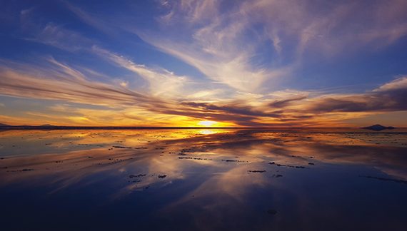 Vibrant sunset reflecting on a tranquil lake with dramatic clouds in the sky.