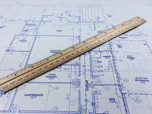 Wooden ruler placed on architectural blueprints, illustrating planning, design, and precision in construction projects.