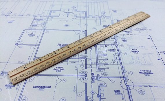 Wooden ruler placed on architectural blueprints, illustrating planning, design, and precision in construction projects.