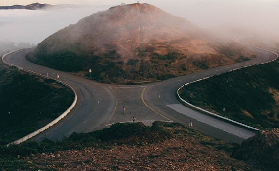 Curved roads meet at foggy mountain, creating a scenic view.