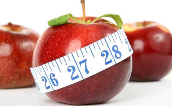 Red apple with measuring tape symbolizes healthy diet and weight loss.