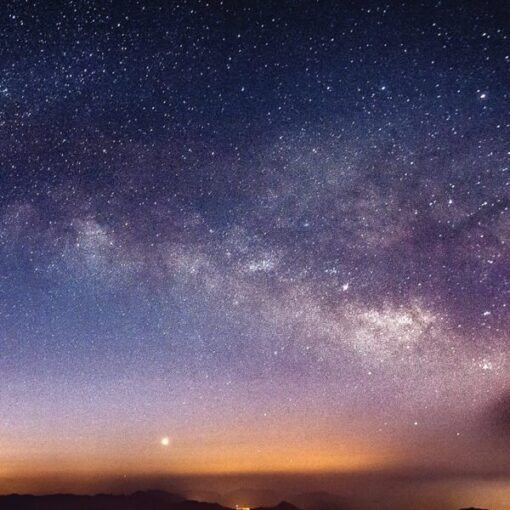 Starry night sky with Milky Way galaxy over a distant horizon, showcasing space beauty and cosmic wonder.