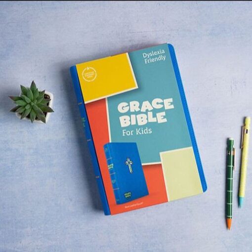 Dyslexia-friendly kids bible on desk with pencils and plant; promotes easy reading for young children.
